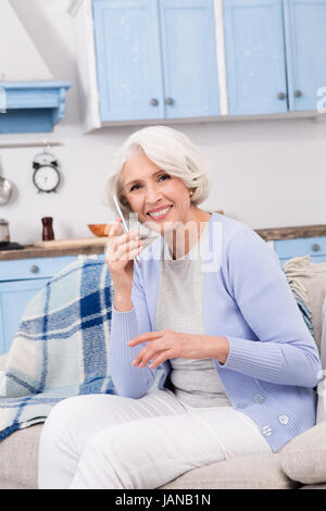 Elderly woman using mobile phone at home Stock Photo