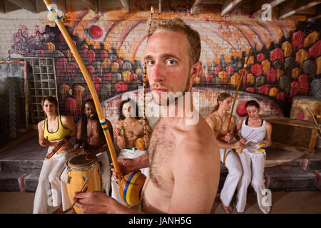 Serious male capoeira performer with group playing music Stock Photo