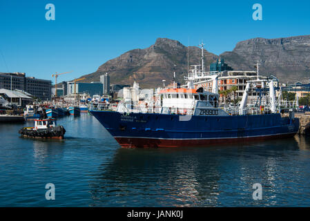 Tug boat pulling a ship out of Cape Town harbour with Table Mountain in the background Stock Photo