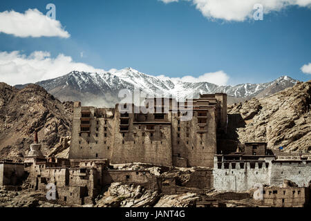 Dramatic location and Leh Palace with the white mountains of the Himalaya creating a beautiful snow capped peaks background a beautiful backdrop Stock Photo