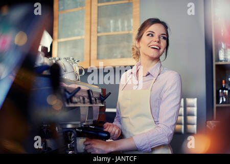 Female barista using coffee maker in cafe Stock Photo