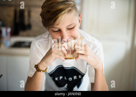 Young caucasian man eating sandwich in kitchen Stock Photo