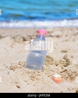 bottle with fresh water stuck in the sand Stock Photo