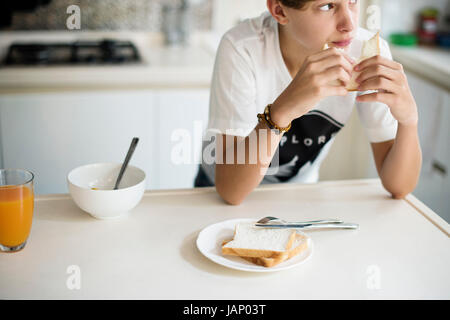 Young caucasian man eating sandwich in kitchen Stock Photo