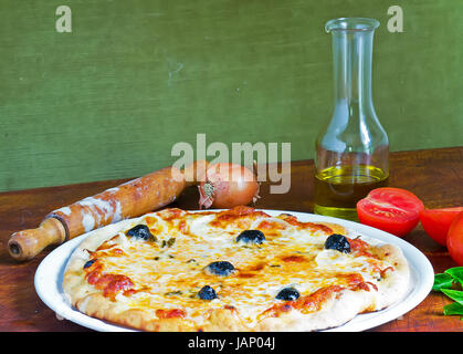 detail of a pizza on a wooden table with ingredients all around Stock Photo