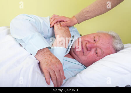 Picture of a sick elderly man in bed with his caregiver Stock Photo