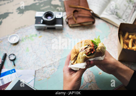 Closeup of hands holding hamburger over map background Stock Photo