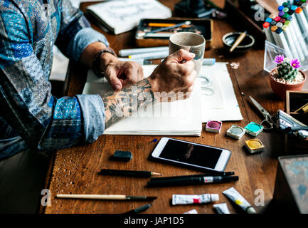 Side view of tattoo artist man working artwrok on wooden table Stock Photo