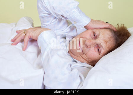 Picture of an elderly woman having a migraine, lying in bed Stock Photo