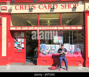 Boy busking playing tin whistle outside shop, Youghal, County Cork, Ireland, Irish Republic Stock Photo