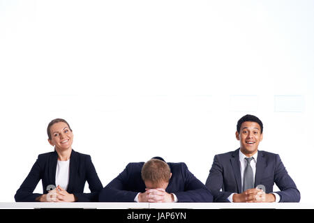 Portrait of smiling business partners looking at camera with their colleague keeping his head on crossed hands Stock Photo