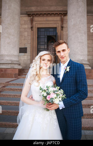 Wedding couple near a church. Wedding couple is hugging each other. Beauty bride with groom . Beautiful model girl in white dress. Man in suit. Stock Photo