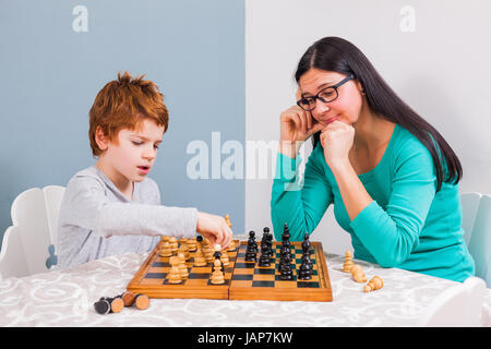 Mother and her son are playing chess at home. Stock Photo