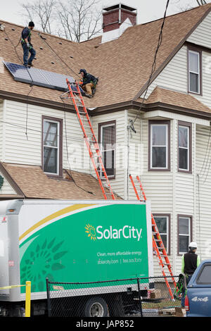 Amsterdam, New York – Jan 20, 2017: Workers install solar panels on a rooftop in the Montgomery Vounty city. Under Andrew Cuomo, the state of NY offer Stock Photo