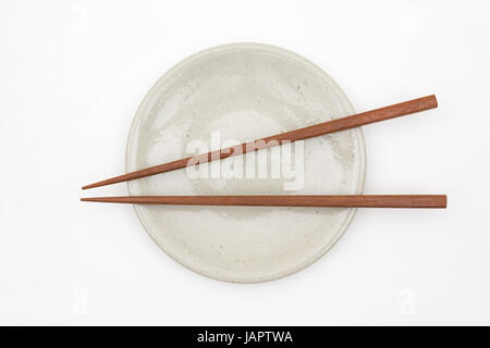 Traditional Japanese wooden chopstick on white ceramic plate Stock Photo