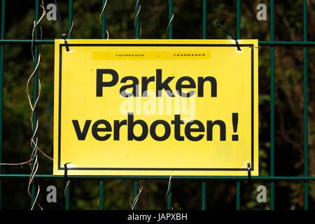 yellow sign no parking on a garden fence Stock Photo