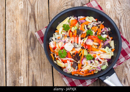 Frozen cooked vegetable mix in frying pan on wooden background,  Stock Photo