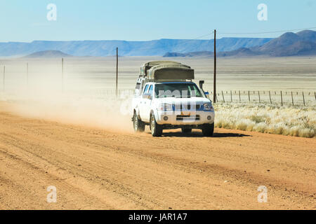 Pickup truck driving fast with dust cloud on desert road Stock Photo
