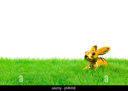 Golden easter bunny, sitting in bright field. Isolated on white. Stock Photo