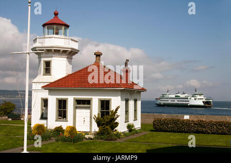 A ferry leaves the dock behind a coastal nautical beacon on puget sound Stock Photo