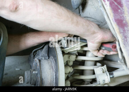 A professional mechanic repairs the car. Tighten the bolt. Stock Photo