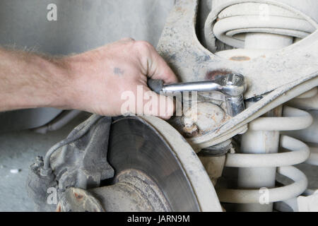 A professional mechanic repairs the car. Tighten the bolt. Stock Photo