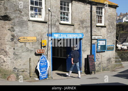 Port Isaac, Cornwall, UK - April 8th 2017: On Fore Street, a sea fisherman walks into the entrance to 'Port Isaac Fishermen Ltd', a fishermens' cooper Stock Photo