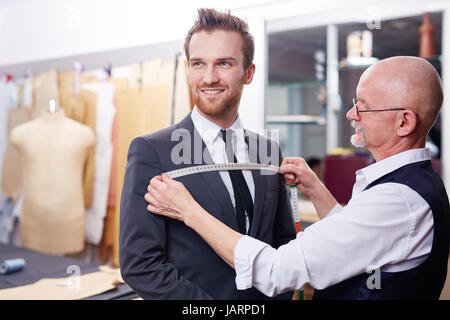 Tailor Measuring Smiling Client in Atelier Stock Photo