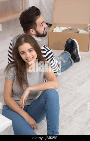 Happy man and woman sitting on the floor tired preparing to relocate to new apartment. Stock Photo