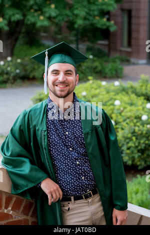 college senior poses for a graduation photo on campus in his cap and jat0bd
