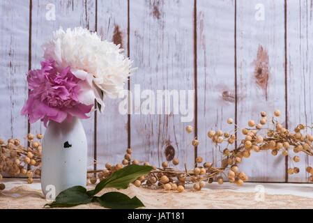 Background of a vintage milk bottle holding peony flowers with wooden background Stock Photo