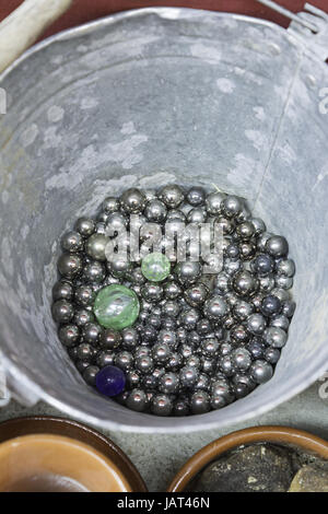 Children playing marbles in metal bucket with fun Stock Photo