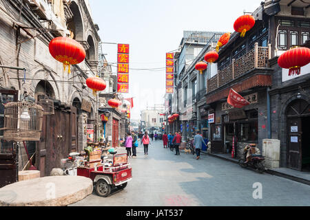 BEIJING, CHINA - MARCH 19, 2017: people on shopping street Dashilan West in Hutong Area in old town. Hutongs are narrow streets protected to preserve  Stock Photo