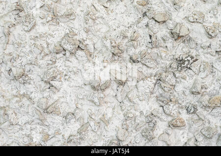 Old white concrete wall with many protruding stones Stock Photo