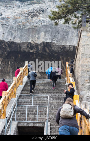 LUOYANG, CHINA - MARCH 20, 2017: tourists climb to cave in Chinese Buddhist monument Longmen Grottoes (Longmen Caves). The complex was inscribed upon  Stock Photo