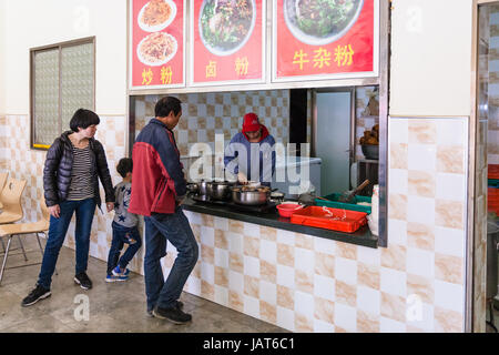 LONGSHENG, CHINA - MARCH 26, 2017: People in cheap urban eatery in Longsheng town. Longsheng is a small city in the south central Chinese province of  Stock Photo