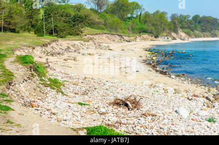 Beach erosion. Erosion has removed large parts of the soil into the sea, leaving stones and steep shorelines. Stock Photo