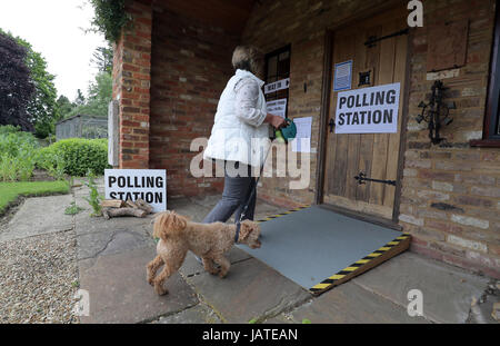 A voter with her dog arrives at a polling station in a guest house annex in Dogmersfield, Hampshire, as voters head to the polls across the UK to vote in the General Election. Stock Photo