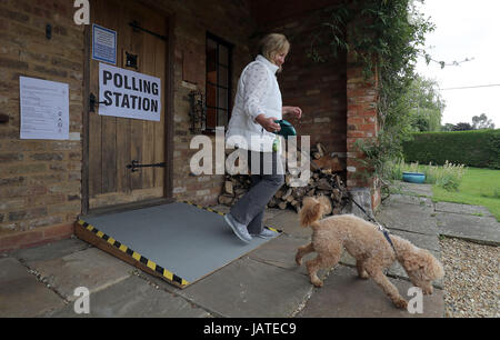 A voter with her dog leaves a polling station in a guest house annex in Dogmersfield, Hampshire, as voters head to the polls across the UK to vote in the General Election. Stock Photo