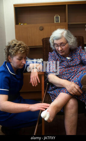 District nurse on a home visit to elderly woman treating wounds on her foot Stock Photo