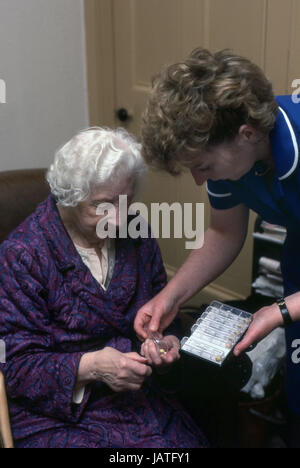 district nurse on a home visit assisting elderly woman with her daily medication Stock Photo