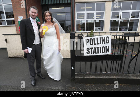 Alliance candidate for West Belfast Sorcha Eastwood casts her vote in the 2017 General Election, with her husband, Dale Shirlow, at a polling station in Lisburn, Northern Ireland, still wearing her wedding dress after they were married earlier in the day. Stock Photo