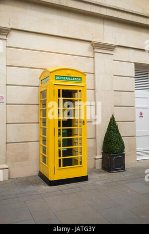 An Automatic Electric Defibrillator, plus first aid equipment and phone installed in a yellow telephone box, Southgate Management Building, Bath, UK Stock Photo