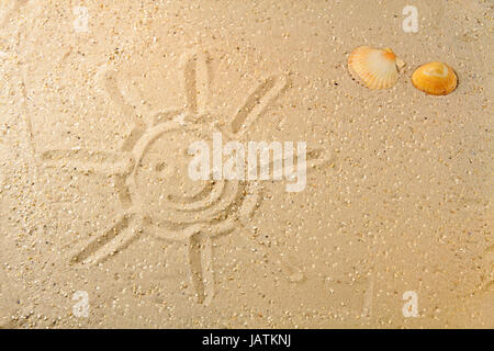 Sonne im Sand gezeichnet mit zwei farbigen Muscheln am Strand Stock Photo