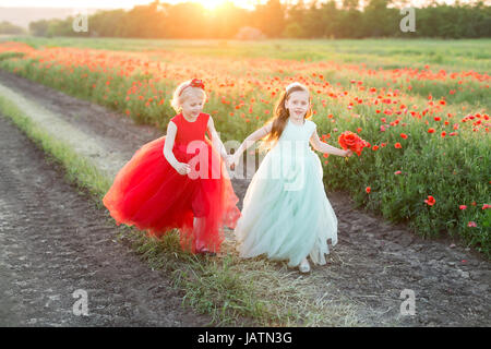 freedom, frendship, country, happiness concept - in gold light of sun two lovely girls in beautiful feast dresses in bright red and light blue shadows Stock Photo