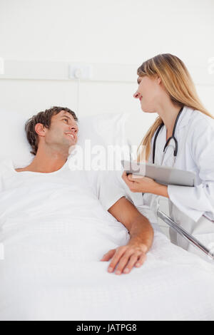 Smiling doctor looking at her patient while standing next to his hospital bed Stock Photo