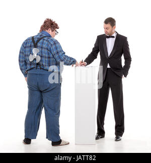 Elegant man in a tuxedo and bow tie standing arguing with an overweight country yokel Stock Photo