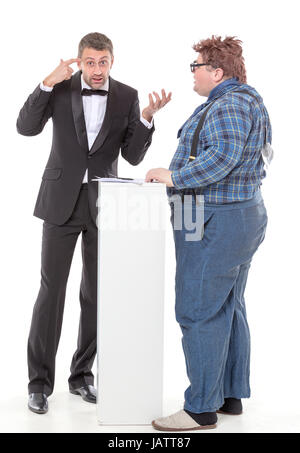 Elegant man in a tuxedo and bow tie standing arguing with an overweight country yokel Stock Photo