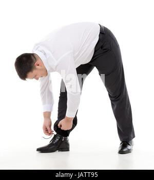 Supple businessman bending down to do up his shoelaces on his stylish leather shoes while dressing in the morning or because they have come loose during the day Stock Photo