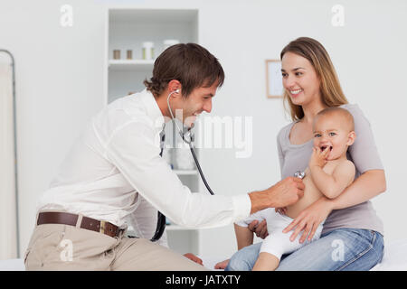 Smiling mother looking at the doctor while holding her baby Stock Photo